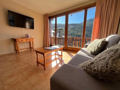a living room with a couch and a large window at Apartaments Font del Poble in Ransol