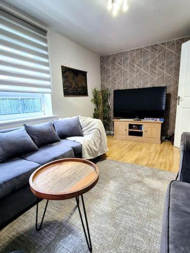 a living room with a blue couch and a flat screen tv at Modern Home2Home - Easy Centre Access & Free Parking in Sheffield