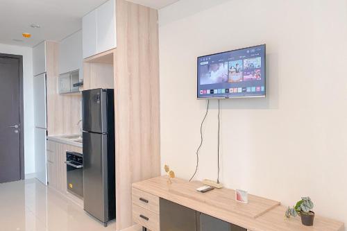 a kitchen with a refrigerator and a tv on the wall at Spacious and Homey Studio at Cleon Park Apartment By Travelio in Jakarta