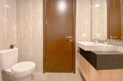 a bathroom with a toilet and a sink at Spacious and Homey Studio at Cleon Park Apartment By Travelio in Jakarta