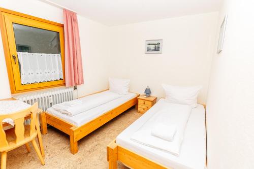 two beds in a room with a table and a window at Naturfreundehaus Brend in Neuweg