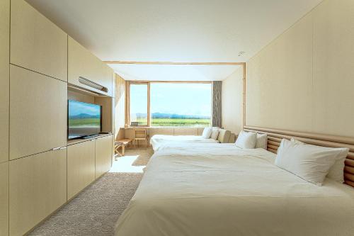a hotel room with three beds and a television at Shonai Hotel Suiden Terrasse in Tsuruoka