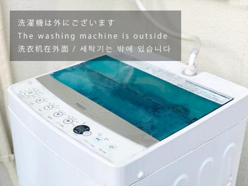 a washing machine with a sign that reads the washing machine is outside at TABISAI HOTEL House 博多 in Fukuoka