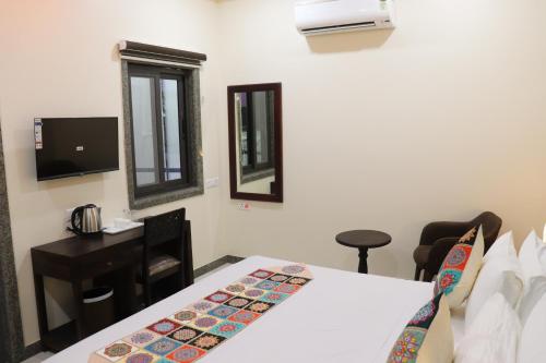 a hotel room with a bed and a desk and mirror at Hotel M R Paradise in Jaisalmer