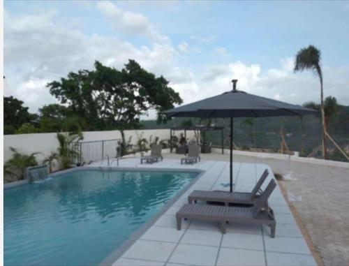 a swimming pool with an umbrella and a bench at Oricha Villa in Ocho Rios