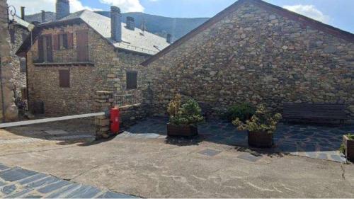a stone building with two potted plants and a bench at Apartament Era de Dalt Barruera in Barruera
