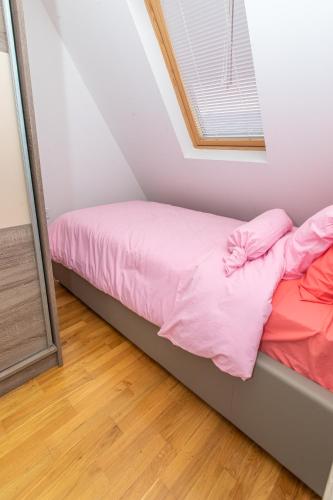 a bed with pink sheets in a room with a window at Luxury Apartments Valentino in Ohrid