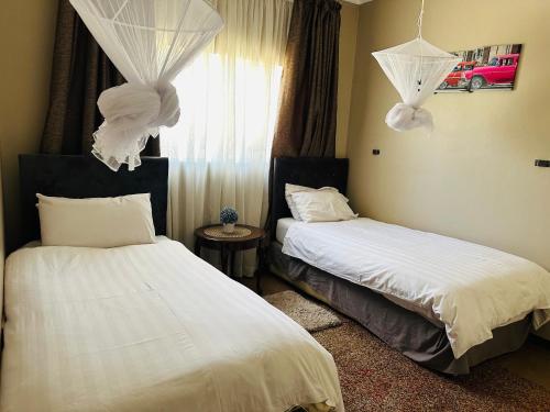 a bedroom with two beds with white sheets and a window at Serene 3 bedroom house in Olympia, Lusaka in Lusaka