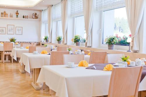 a restaurant with white tables and chairs and windows at Ferienhotel Mühlleithen in Klingenthal