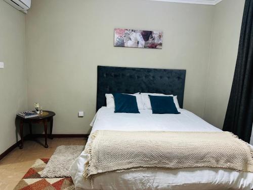 a bedroom with a large bed with blue pillows at Serene 3 bedroom house in Olympia, Lusaka in Lusaka