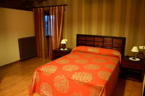 a bedroom with a orange bed and two night stands at Casa Teillor in Moldes