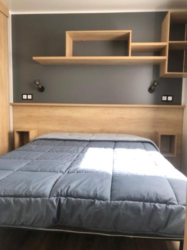 un lit avec une tête de lit en bois dans une chambre dans l'établissement Les dunes de Contis Chez Edith océan pins et détente assurée dans camping 4 étoiles, à Saint-Julien-en-Born