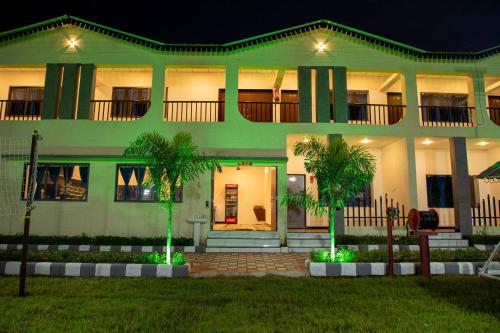 a green building with palm trees in front of it at VITS Select Diamond Resort Sasan Gir in Talala