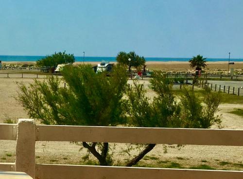 a fence with a bush in front of a beach at Chalet Alaric & Jacuzzi Ilot 1 rang1! VUE MER! 4rooms! CLIM 10p 24H24 in Gruissan