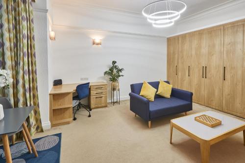 een woonkamer met een blauwe stoel en een bureau bij Host & Stay - Thamesview in Staines