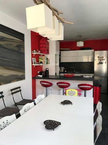 - une cuisine avec une table blanche et des murs rouges dans l'établissement Grande maison à 300m mer et commerces, parking 2places et linge inclus, à Le Touquet-Paris-Plage