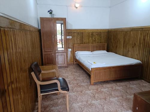 a bedroom with a bed and a chair in it at Trilan Cottages - Donnington Road in Kotagiri