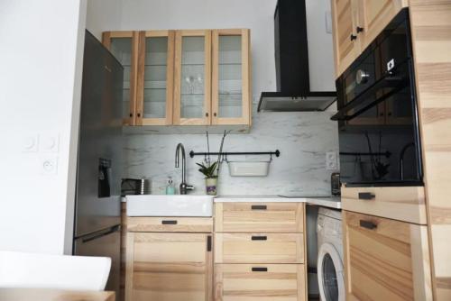 une cuisine avec des armoires en bois et un évier dans l'établissement Chez Pascal Sissi -New Appart, Ile Nantes, CCgrés, à Nantes