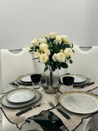 une table avec des assiettes et un vase de roses blanches dans l'établissement Studio 36mt2 a 5 min a pied boulevard de Belgique MC, à Beausoleil