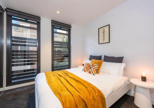 Un dormitorio con una cama y dos ventanas. en Elwood stylish apartment in botanical location near beach, en Melbourne