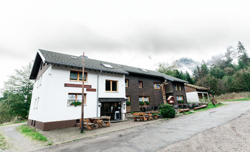 a white building with picnic tables in front of it at Naturfreundehaus Brend in Neuweg