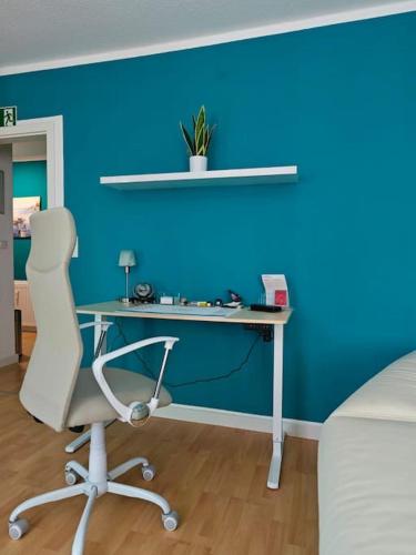 a desk with a chair in a room with a blue wall at Ferienwohnung Freedom 2 Sky Terrasse High End in Northeim