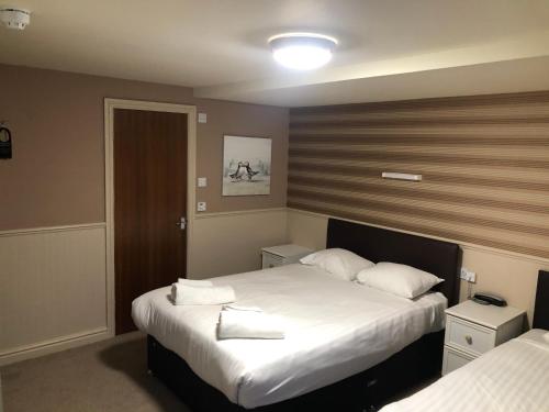 a bedroom with two beds with white sheets at Lyndene Hotel in Blackpool