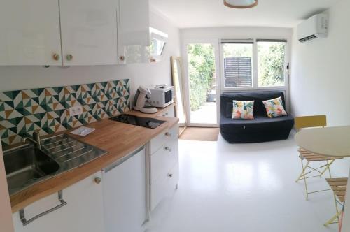 a kitchen and living room with a couch in the background at Charmant studio - Terrasse - Parking gratuit in Montpellier