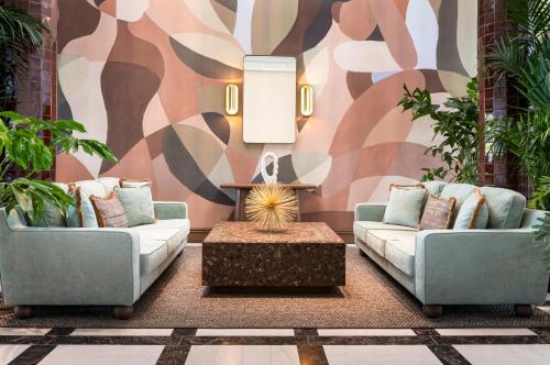 two couches and a coffee table in a room with a mural at Brunfels Hotel, in the Unbound Collection by Hyatt in Mainz