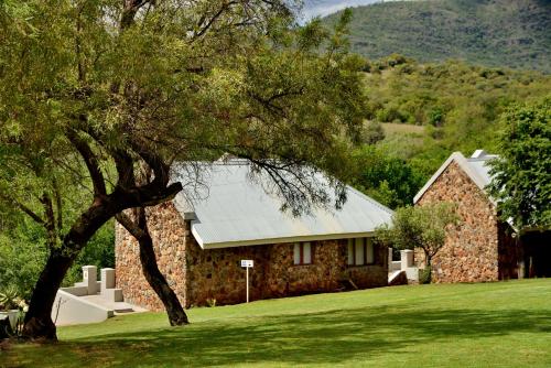 a stone house with a tree in front of it at Thanda Manzi Country Hotel in Centurion