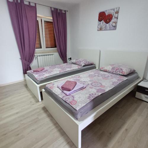 two beds in a room with purple curtains at Apartman Nona in Motovun
