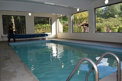 a woman standing next to a swimming pool with windows at Potting Shed in Shadoxhurst