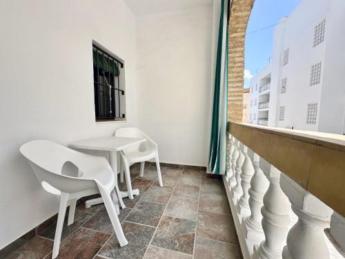 a balcony with white chairs and a table and a window at Apartamentos Turísticos Santo Rostro in Chipiona