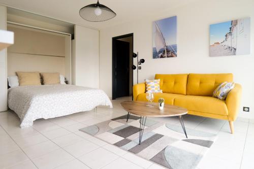 un salon avec un canapé jaune et une table dans l'établissement Appartement avec superbe vue sur le port de plaisance des Sables d'Olonne - 4 personnes, à Les Sables-dʼOlonne