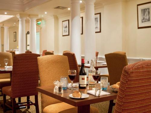 a restaurant with a table with wine bottles and glasses at Winchester Wessex Hotel by Sunday in Winchester