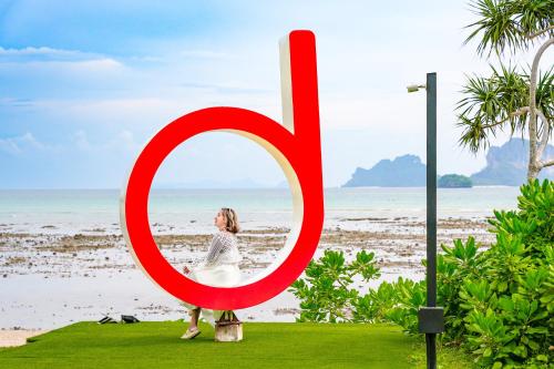 a woman sitting in a large red number six on the beach at Tinidee Hideaway Tonsai Beach Krabi - SHA Extra Plus in Tonsai Beach
