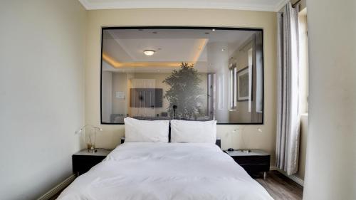 a bedroom with a large white bed with a large mirror at 4 on Pritchard Luxury Suites in Johannesburg