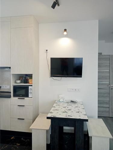 a kitchen with a table and a tv on the wall at Family Apartments Dorobok in Lviv