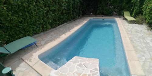 - une piscine à côté d'une haie avec une chaise et une table dans l'établissement Charmant studio - Terrasse - Parking gratuit, à Montpellier