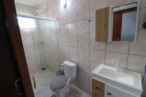 um banheiro com chuveiro, vaso sanitário e pia em Suíte Hospedagem Ohana em Penha