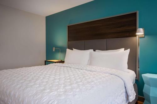 a bedroom with a large white bed with a blue wall at Tru By Hilton Merrillville in Merrillville
