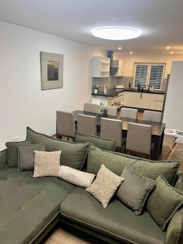 a living room with a green couch and a dining room at Vila EMMA in Prostějov