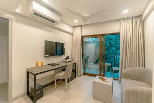 a room with a desk with a television and a couch at Comfort Inn Elite in Jua