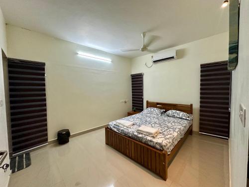 a bedroom with a bed in a room with windows at Padmanabham Villa Blissful 3BHK Stay Near Airport in Trivandrum