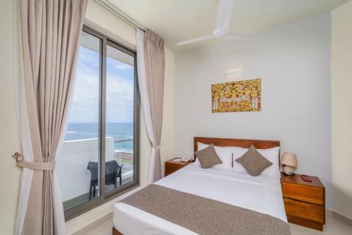 a bedroom with a bed and a large window at Marine Suites in Colombo