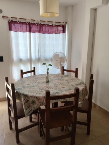 uma mesa de jantar com cadeiras e um vaso de flores em cima. em Maraja em Mar de Ajó
