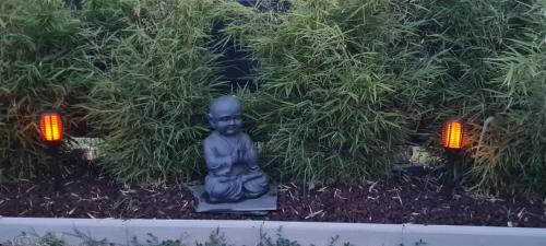 a statue of a buddha in a garden with two lights at CA LA MIMI, avec vue sur le mont Canigó pour 8 personnes in Prades