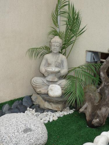a statue sitting on a rock in a garden at CA LA MIMI, avec vue sur le mont Canigó pour 8 personnes in Prades