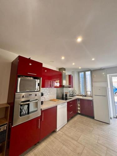 une cuisine avec des armoires rouges et des appareils blancs dans l'établissement La Maison de Sainte-Eulalie, à Roubia