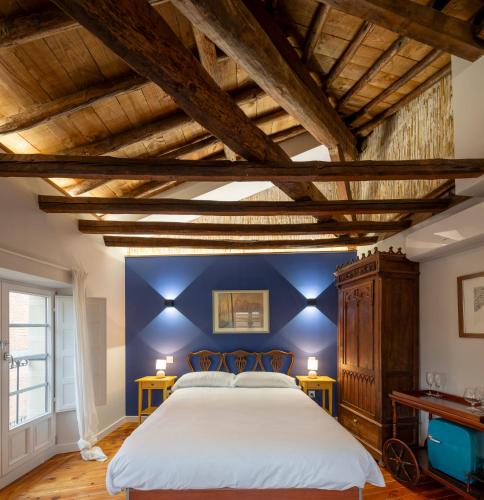a bedroom with a large bed with blue walls and wooden beams at Apartamento con PARKING- Altior - Catedral Homes in Ávila